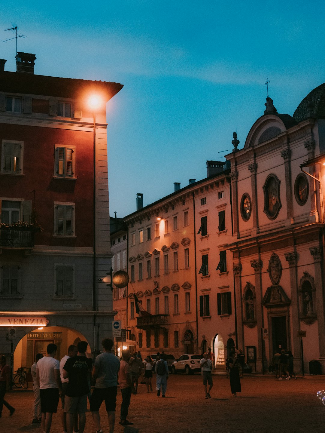 Persone che passeggiano in una storica piazza europea al crepuscolo.